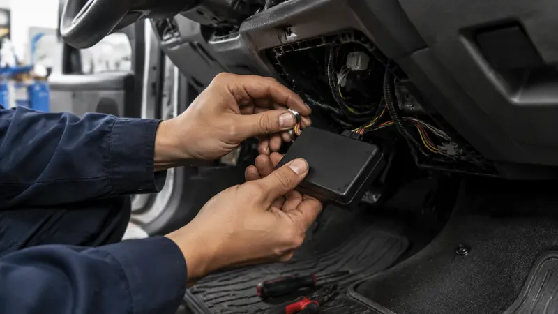 Técnico de Sistemtrack instalando un equipo GPS oculto bajo el tablero de un vehículo